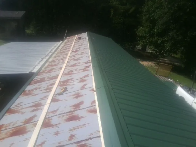 Old rusted panels beside newly installed green metal roofing — Wind Damage Roof Repair by Roofing Brothers in Kaufman
