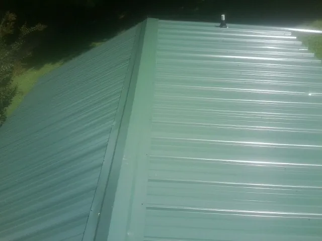 New green metal panels meeting at the ridge of a roof — Flat Roof Repair work by our crew in Kaufman