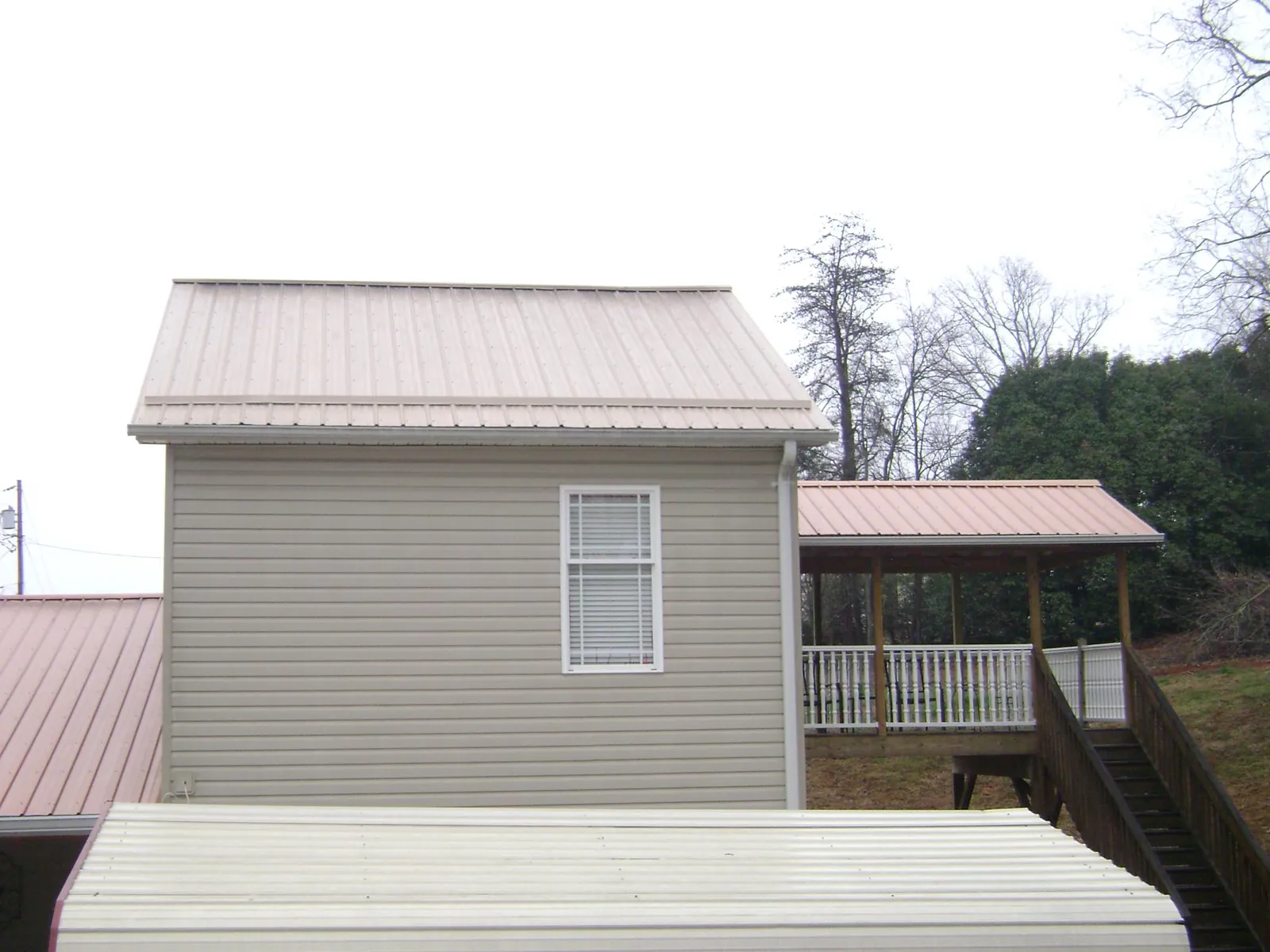 Tan metal roofs on a two story addition and attached porch, from a Roof Replacement job in Kaufman
